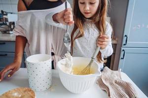 mãe ensina sua filha a cozinhar comida foto