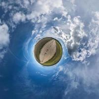 pequeno planeta no céu azul com belas nuvens. transformação do panorama esférico 360 graus. vista aérea abstrata esférica. curvatura do espaço. foto