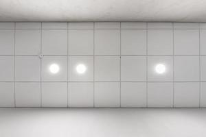 teto suspenso de cassete com lâmpadas de halogênio redondos e construção de drywall em sala vazia em apartamento ou casa. tecto falso branco e forma complexa. olhando para cima foto