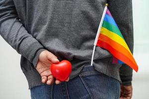 mulher asiática segurando hert vermelho com bandeira do arco-íris, direitos do símbolo lgbt e igualdade de gênero, mês do orgulho lgbt em junho. foto