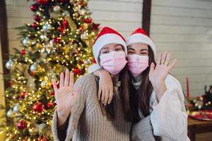 duas garotas com máscaras protetoras, olhando para a câmera e acenando foto