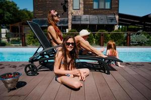 uma linda família está relaxando à beira da piscina foto