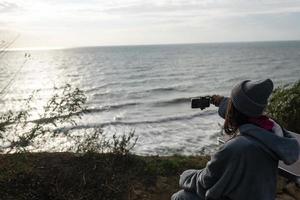 jovem tira uma foto em um smartphone da paisagem marinha