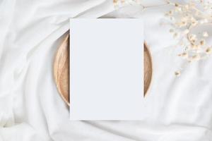 uma mesa com flores de algodão e placa de madeira ou bandeja e cartão em branco. foto