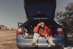 mulher jovem e atraente descansando no porta-malas de um carro foto