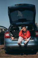 mulher jovem e atraente descansando no porta-malas de um carro foto