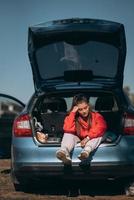 mulher jovem e atraente descansando no porta-malas de um carro foto