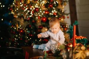 garotinho brincando na árvore de natal foto