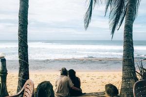 casal sentado sob palmeiras foto