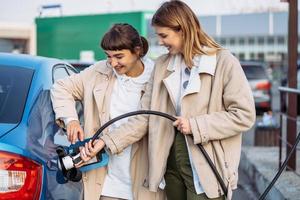 amigos felizes reabastecer o carro no posto de gasolina. viagem de férias foto