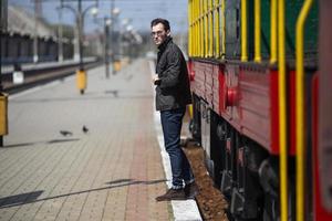 um homem vestido de jeans no fundo do trem e da estação foto
