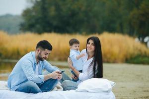 família jovem feliz relaxando juntos no lago foto