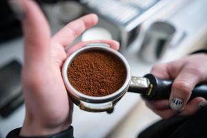 barista segurando porta-filtro com café moído foto