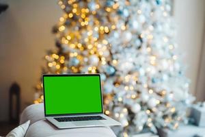 laptop com tela verde - chromakey perto de decorações de ano novo. tema de natal. foto