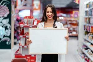 mulher morena sorridente segurando o quadro branco em branco foto