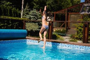 garota feliz pulando na piscina foto