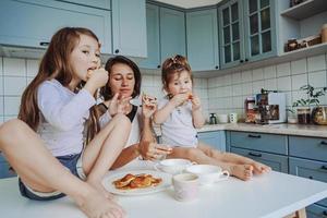 mãe e duas filhas comem panquecas foto