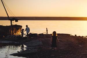 duas crianças caminham pela praia, noite de verão foto