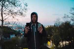 jovem no parque tira uma foto em dois smartphones