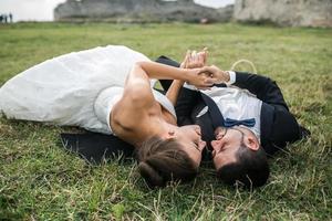 casal de noivos deitado na grama foto