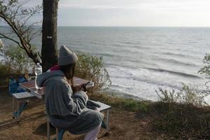 jovem tira uma foto em um smartphone da paisagem marinha