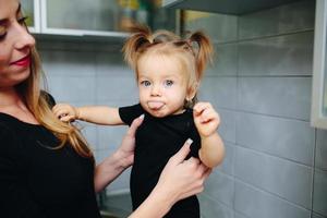 mãe com filha em pé na cozinha foto