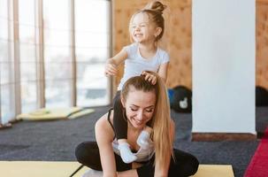 uma filha pequena senta-se nas costas de sua mãe foto