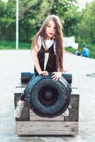 menina pré-escolar sentada em cima de um canhão foto
