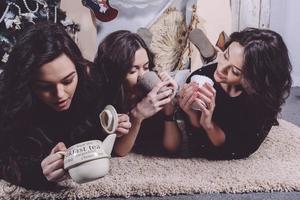 linda garota comendo biscoitos de natal e bebendo chá enquanto estava deitado em um tapete. apartamento vintage decorativo. foto