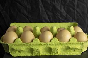 caixa de papel com ovos de galinha fresca de fazenda em fundo preto foto