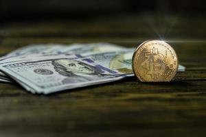 moeda de criptomoeda bitcoin e dólares em uma superfície de madeira foto