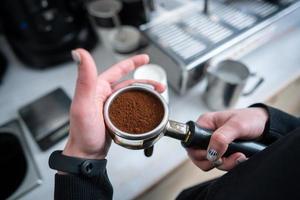 barista segurando porta-filtro com café moído foto