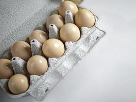 caixa de papel com ovos de galinha fresca de fazenda em fundo branco foto