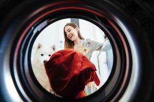 jovem em casa coloca o vestido na máquina de secar. foto
