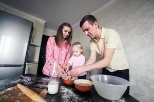 pai, mãe e filha juntos na cozinha foto