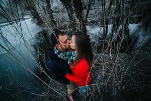 lindo casal posando perto de um rio congelado foto