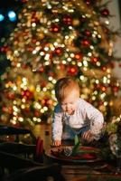 garotinho brincando na árvore de natal foto