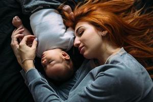 mãe feliz com bebê deitado juntos na cama foto