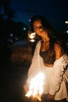 jovem com tocha na praia à noite foto