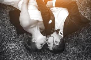 casal de noivos deitado na grama foto