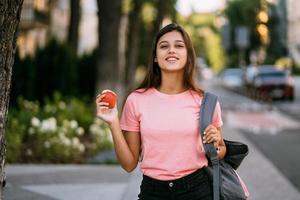 jovem mulher segurando a maçã contra um fundo de rua foto