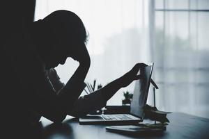 estresse mulher de negócios do trabalho duro, depressão no escritório. trabalhadora cansada e ansiosa com infeliz no trabalho problemático. jovem empresária sentada triste frente do computador portátil na mesa. foto