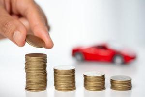 veículo de brinquedo de carro com dinheiro de moeda de pilha no fundo. planejamento para gerenciar os custos de financiamento de transporte. conceito de negócio de seguro de carro, economizando compra - venda com impostos e empréstimo para carro novo. foto