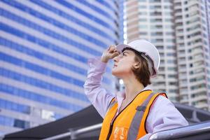 engenheira caucasiana está olhando por cima do prédio enquanto inspeciona o projeto de construção para arquitetura moderna e conceito de desenvolvimento imobiliário