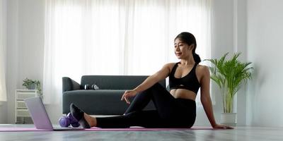 retrato de uma jovem mulher asiática bonita alongamento aquecimento exercício exercício ioga posição em casa na sala de estar. estilo de vida esportivo de cuidados de saúde menina ásia. foto