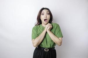 um retrato de uma mulher asiática chocada vestindo uma camiseta verde, isolada por um fundo branco foto