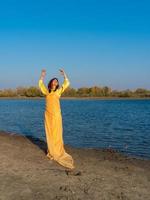 mulher com roupas amarelas e uma capa transparente posando à beira do lago. estilo de vida positivo foto