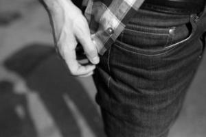 um homem ajusta sua camisa sobre fundo de jeans foto