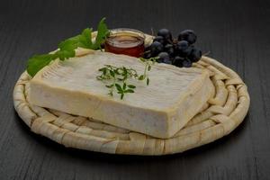 queijo brie na tábua de madeira e fundo de madeira foto