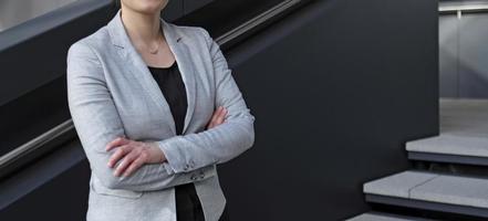 profissional feminina anônima em uma camisa preta e paletó cinza em um ambiente urbano foto